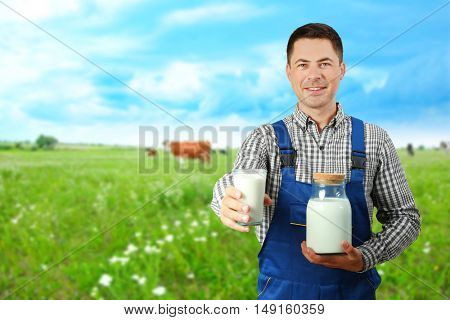 Milkman with cup and jar on on blurred meadow background