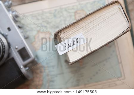 Holiday idea, text and a old map with a vintage camera