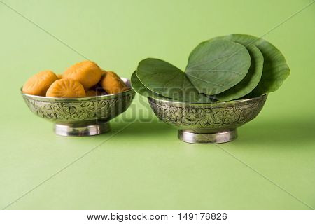 indian festival dussehra or vijayadashmi or ayudh puja, showing apta leaf or Bauhinia racemosa with traditional indian sweets pedha in silver bowl