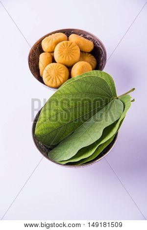 indian festival dussehra or vijayadashmi or ayudh puja, showing apta leaf or Bauhinia racemosa with traditional indian sweets pedha in silver bowl
