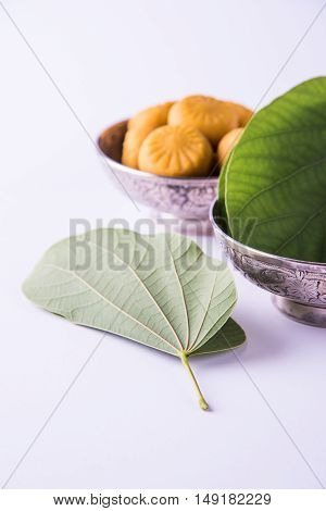 indian festival dussehra or vijayadashmi or ayudh puja, showing apta leaf or Bauhinia racemosa with traditional indian sweets pedha in silver bowl
