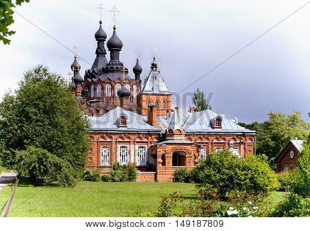A beautiful Orthodox temple located on a hill surrounded by flowers and plants: arborvitae blue spruce shrubs.