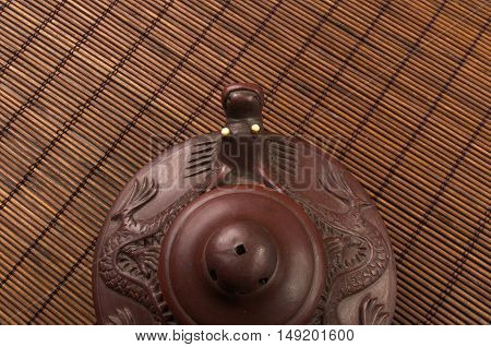 brown Chinese teapot of Yixing clay with traditional ornament on bamboo Mat