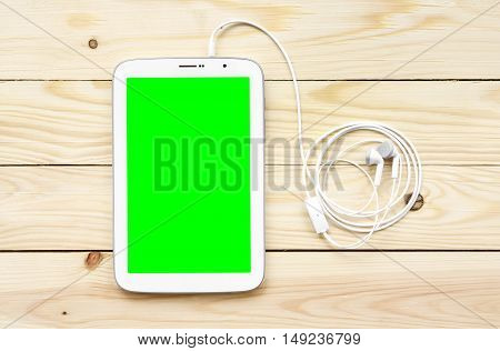 white tablet green screen display with earbuds on top view wood table included clipping path for tablet display