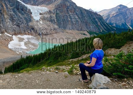 Woman sitting on a stone above glacier lake. Alberta. Canada.