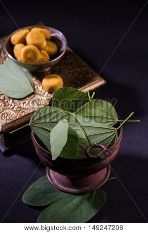 indian festival dussehra or vijayadashmi or ayudh puja, showing apta leaf or Bauhinia racemosa with traditional indian sweets pedha in silver bowl