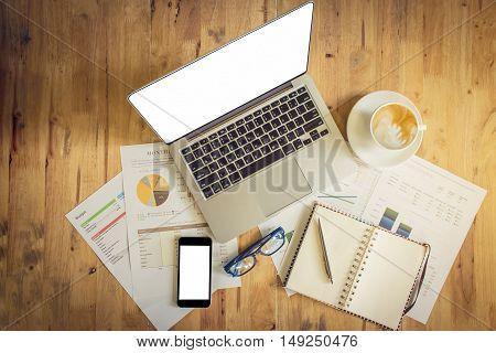 Stock market chart and Smartphone and laptop and pen and notebook on wood desk in the office wich vintage effect.
