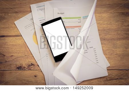smart pone over stock maket chart on wood desk. vintage effect. Smartphone with blank screen and can be add your texts or others on screen.
