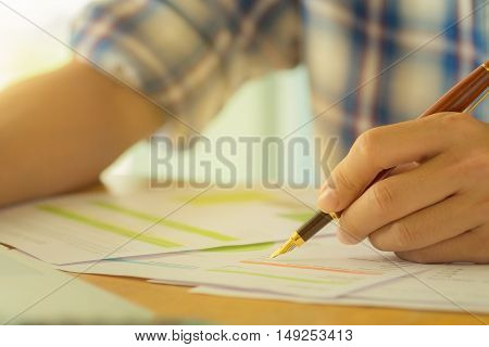 hand hold fountain pen pointing stock maket chart in office. vintage effect.