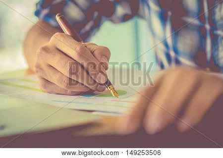 hand hold fountain pen pointing stock maket chart in office. vintage effect.