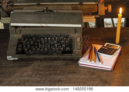 Vintage typewriter white book calculator pencil and candlelight on old wooden touch-up in still life concept