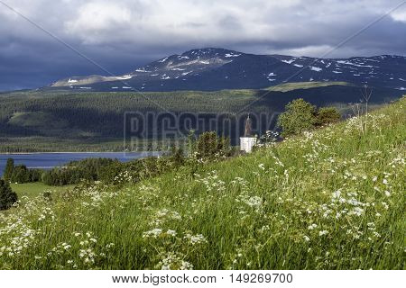 KALL, SWEDEN ON JULY 03. Outdoor view of the church, flowers and the surrounding on July 03, 2016 in Kall, Sweden. Forest and mountains in the background. Editorial use.