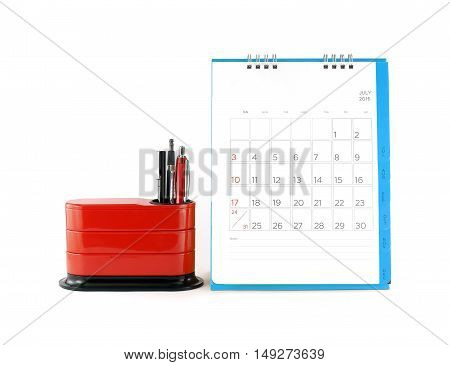 close up blue desk calendar with days and dates in july 2016 and red desk organizer isolated on white background, calendar with blank lines for write note and stationery, office equipment on tidy desk