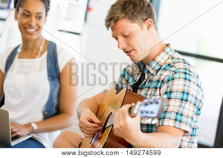 Students sitting on the floor with one playng guitar
