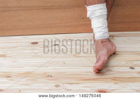 Gauze bandage of physician the treating case with ankle Injured on wooden floor background