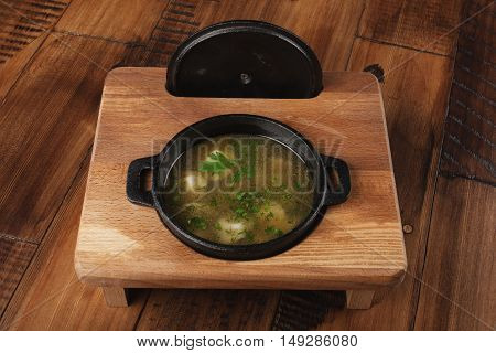 Cooked meat dumplings (pelmeni, chuchpara) in a black pan. wooden background.