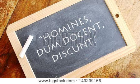 Homines dum docent discunt. A Latin phrase, usually translated into English as Men learn while they teach.