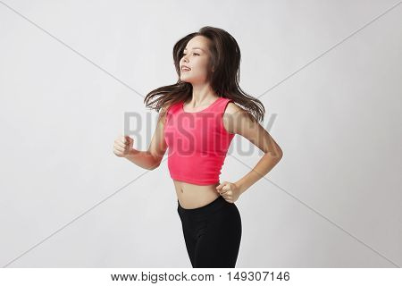 Running fitness woman isolated. Female runner in sporty pink fitness outfit jogging isolated on white background. Beautiful mixed race Asian Caucasian fitness model training.