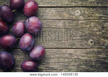 Fresh ripe plums on old wooden table. Top view.