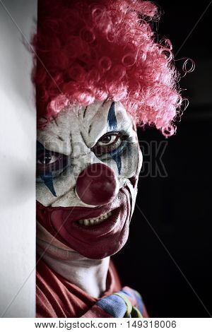 portrait of a scary evil clown against a dark background
