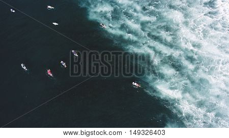 Top view aerial photo from drone of a group of professional surfers having training with instructors in sea with amazingly beautiful swell waves with copy space for your adverting text message