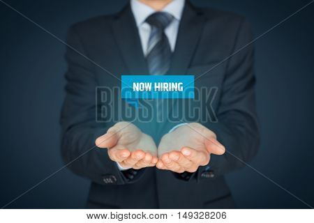 Now hiring - human resources concept. Businessman (recruiter, HR staffer) hold virtual label with text.