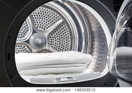 Stacked clean white towels inside washing machine drum. Clean concept. Laundry. Closeup of open washing machine.