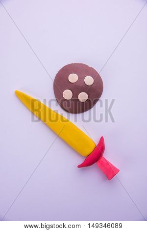 model of sword and shield made up of play dough or playdough or colourful clay, selective focus isolated over white background