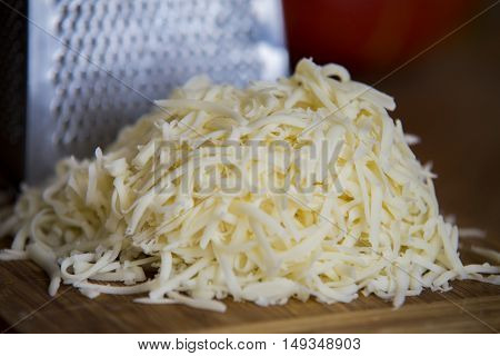 Shredded Mozzarella Cheese On A Cutting Board With A Grater