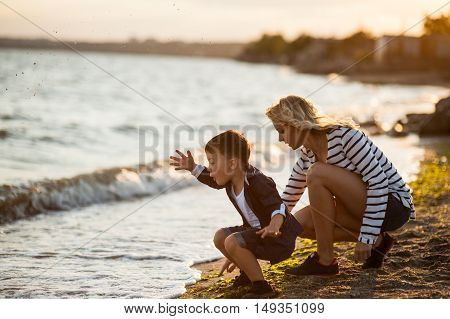 Beautiful woman with a child of four years playing on the beach near the sea