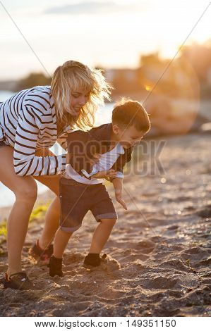 Beautiful woman with a child of four years playing on the beach near the sea