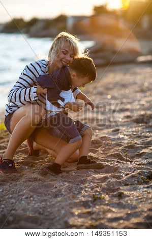 Beautiful woman with a child of four years playing on the beach near the sea