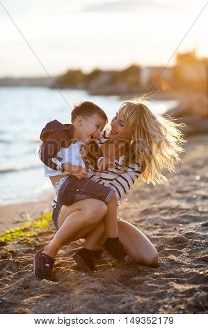 Beautiful woman with a child of four years playing on the beach near the sea