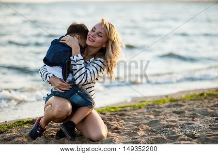 Beautiful woman with a child of four years playing on the beach near the sea