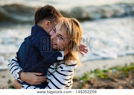 Beautiful woman with a child of four years playing on the beach near the sea