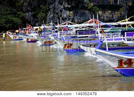  PALAWAN PHILIPPINES FEBRAURY 11 2016, Longtail boats line the beach near the cave entrance of Puerto Princesa subterranean underground river - One of the 7 New Wonders of Nature