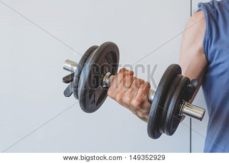 Man lifting weights against a white wall. Space for copy