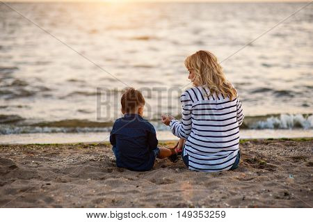 Beautiful woman with a child of four years playing on the beach near the sea