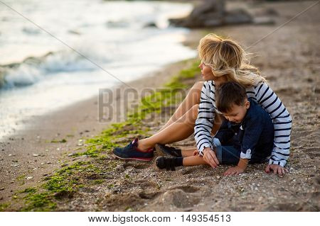 Beautiful woman with a child of four years playing on the beach near the sea