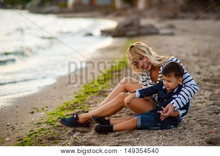 Beautiful woman with a child of four years playing on the beach near the sea