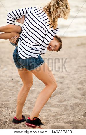 Beautiful woman with a child of four years playing on the beach near the sea