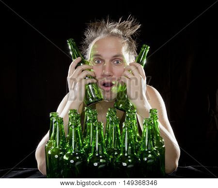 The tipsy man sits with a heap of beer bottles a hangover