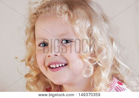 little curly blond Caucasian girl looking dreamily into the distance light smile