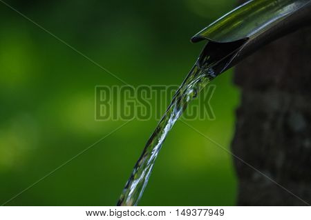 Close up of running water from a tap with green background