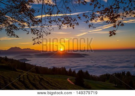 Fog surrounding town Zug and Zugersee during the sunset with the Pilatus and Swiss Alps in the background