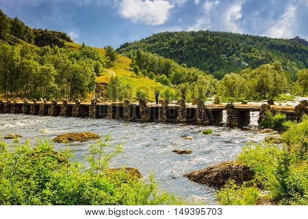 Tourist woman standing on stone slab bridge Terland Klopp in Norway Dalane region.