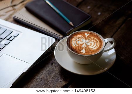 Latte Art Cup of Coffee and laptop on wood