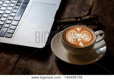 Latte Art Cup of Coffee and laptop on wood