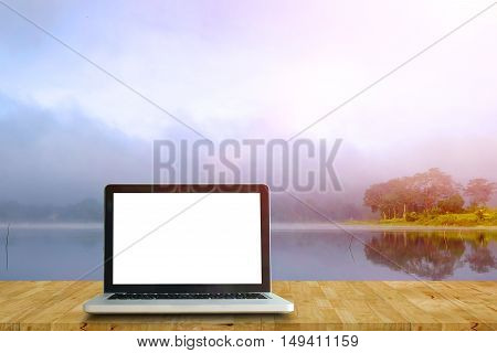 Laptop on wood floor perspective on the lake and forest backgrounds.Mock up for display or montage of productBusiness presentation