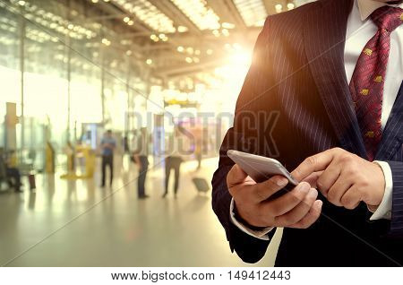 Businessman hand using smartphone at Check in Counter and Passengers in a airport departure terminal.